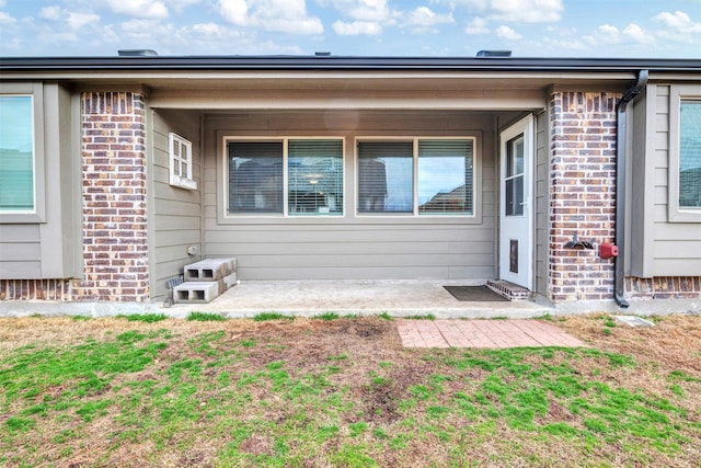 entrance to property featuring a patio area and a lawn