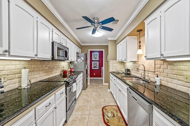 kitchen with light tile patterned flooring, sink, hanging light fixtures, appliances with stainless steel finishes, and white cabinets