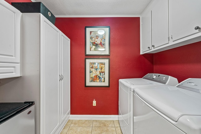 laundry area with cabinets, washer and clothes dryer, a textured ceiling, and light tile patterned floors