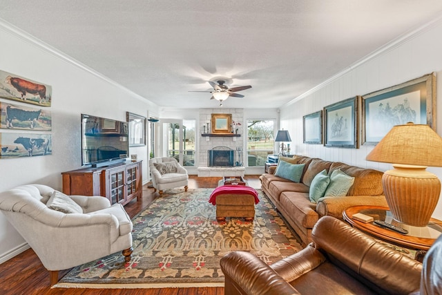 living room with crown molding, a stone fireplace, hardwood / wood-style floors, and ceiling fan