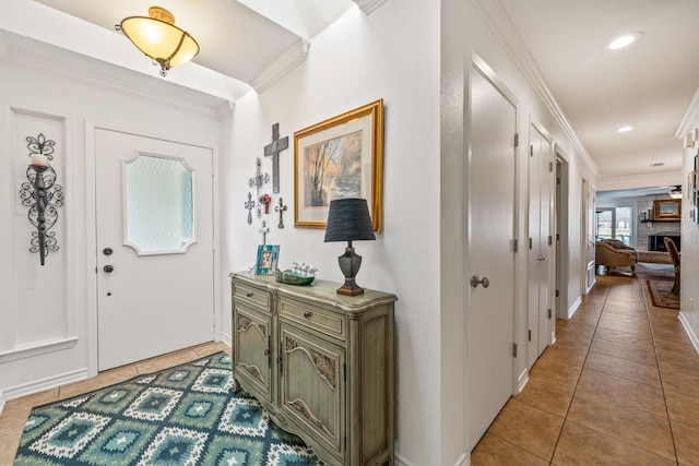 entryway featuring light tile patterned floors, crown molding, and a fireplace