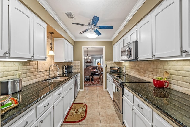 kitchen with appliances with stainless steel finishes, sink, white cabinets, and decorative light fixtures