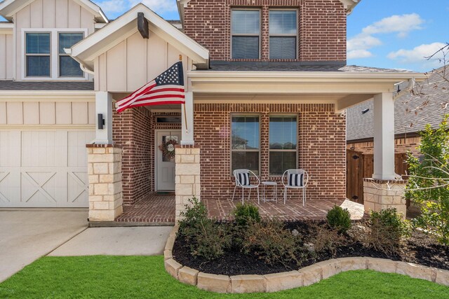 view of front facade featuring a porch, board and batten siding, concrete driveway, an attached garage, and brick siding