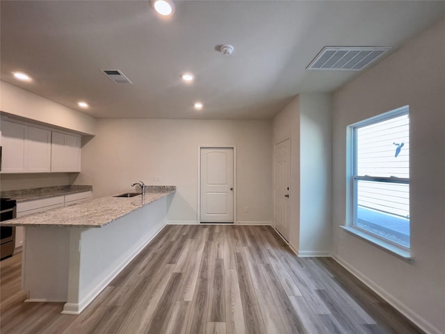 231 Marsh Ln, Princeton, TX 75407 - kitchen with sink, white cabinetry, light stone counters, light hardwood / wood-style floors, and kitchen peninsula