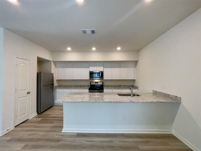 231 Marsh Ln, Princeton, TX 75407 - kitchen featuring white cabinetry, sink, light hardwood / wood-style floors, kitchen peninsula, and stainless steel appliances