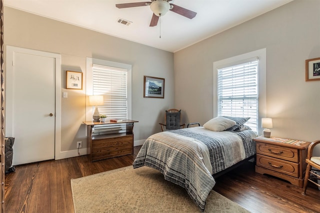 bedroom featuring a ceiling fan, visible vents, dark wood finished floors, and baseboards