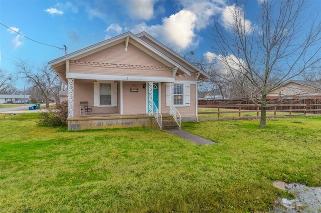 view of front of house with a porch, a front yard, and fence