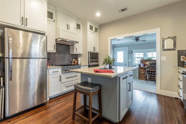 kitchen with white cabinets, glass insert cabinets, a center island, stainless steel appliances, and light countertops