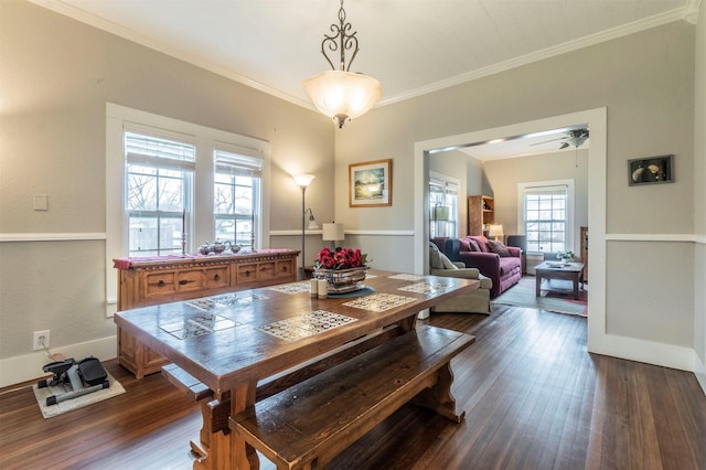 dining area featuring dark wood-type flooring, ornamental molding, and baseboards