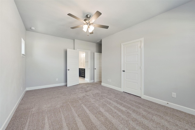 unfurnished bedroom with ensuite bath, light colored carpet, and ceiling fan