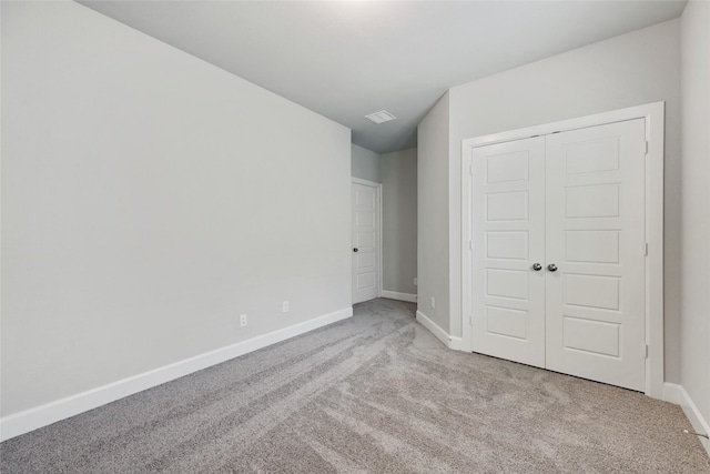 unfurnished bedroom with light carpet and a closet