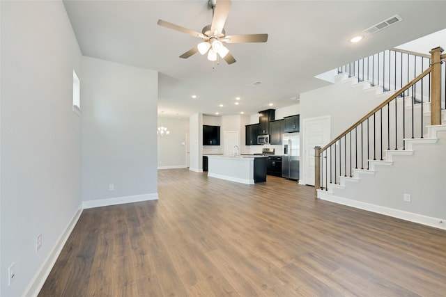 unfurnished living room with sink, dark hardwood / wood-style floors, and ceiling fan with notable chandelier