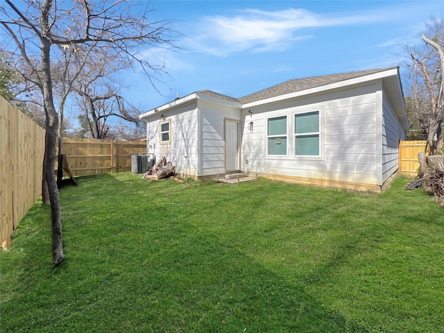 rear view of house with central air condition unit, a yard, and a fenced backyard