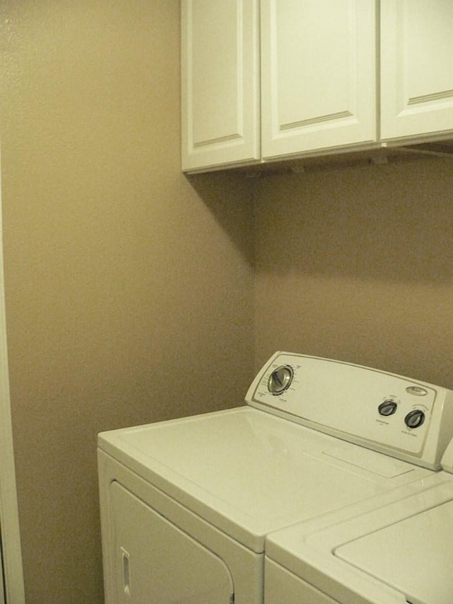 clothes washing area featuring cabinets and washing machine and clothes dryer