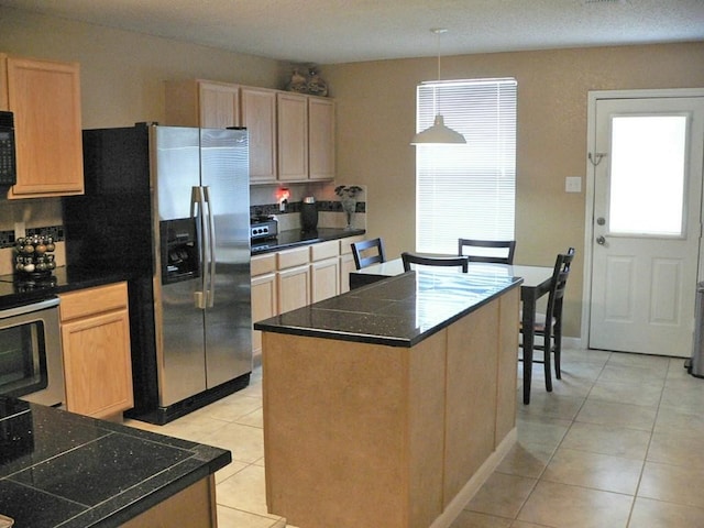 kitchen featuring light tile patterned floors, appliances with stainless steel finishes, tasteful backsplash, a kitchen island, and light brown cabinetry