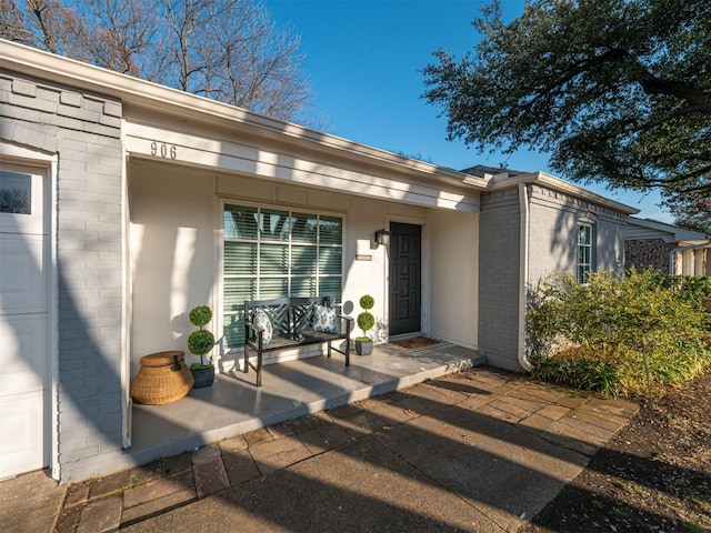 doorway to property with a garage and brick siding