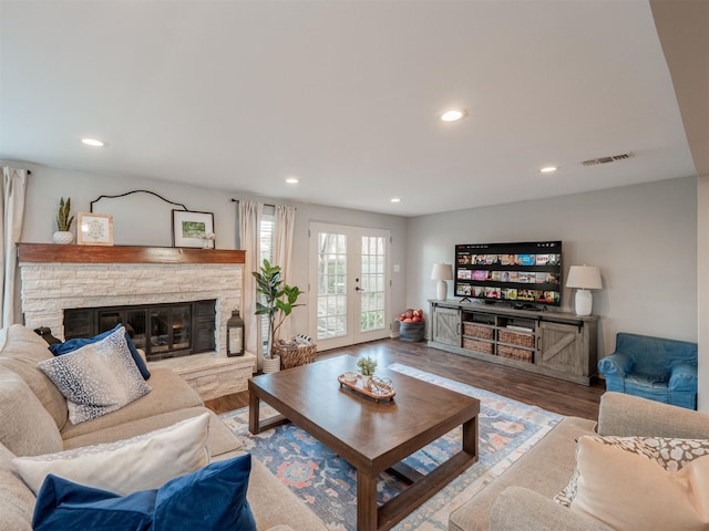 living area featuring visible vents, wood finished floors, a stone fireplace, french doors, and recessed lighting