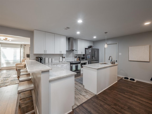 kitchen featuring stainless steel appliances, visible vents, white cabinetry, wall chimney range hood, and wood finished floors