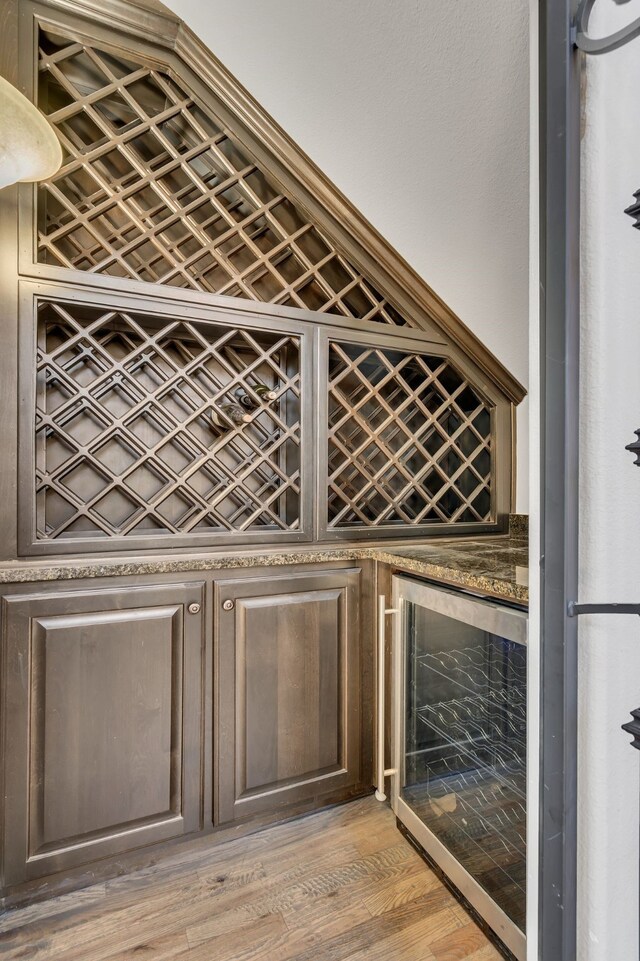 wine room with a bar, light wood-style floors, and beverage cooler
