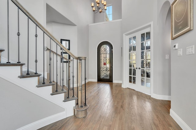 foyer featuring a high ceiling, french doors, a chandelier, and wood-type flooring