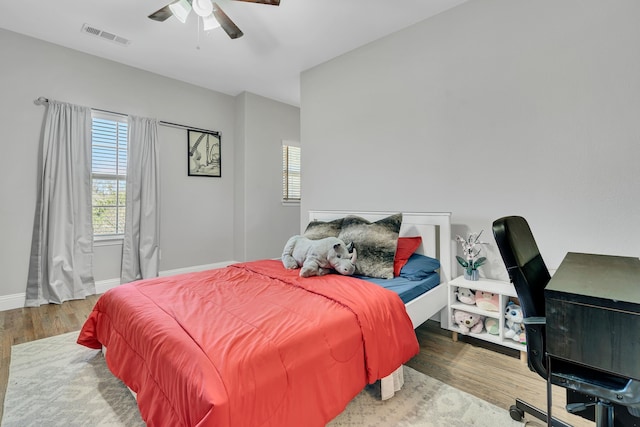 bedroom featuring wood finished floors, baseboards, a ceiling fan, and visible vents