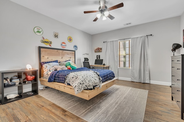 bedroom with visible vents, baseboards, ceiling fan, and wood finished floors