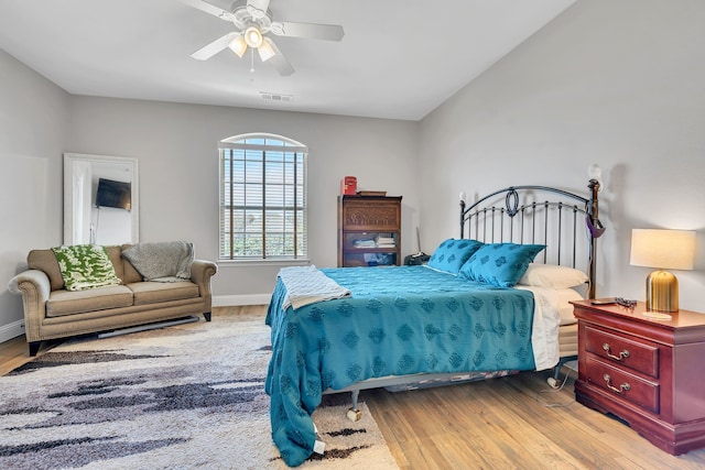bedroom featuring visible vents, baseboards, a ceiling fan, and wood finished floors