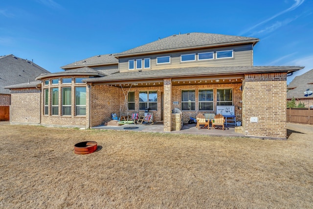 rear view of property with a patio, a lawn, brick siding, fence, and a shingled roof