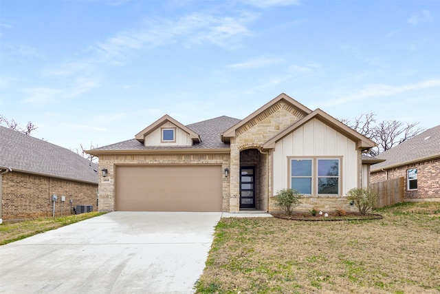 view of front facade with concrete driveway, stone siding, an attached garage, cooling unit, and a front yard