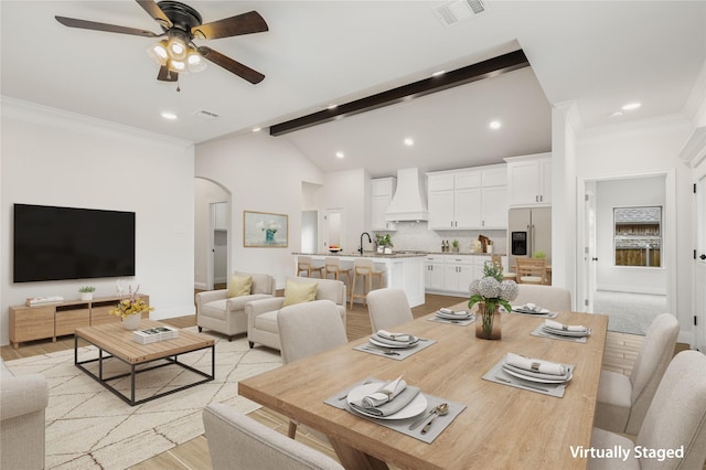 dining space with visible vents, arched walkways, ornamental molding, light wood-type flooring, and beam ceiling