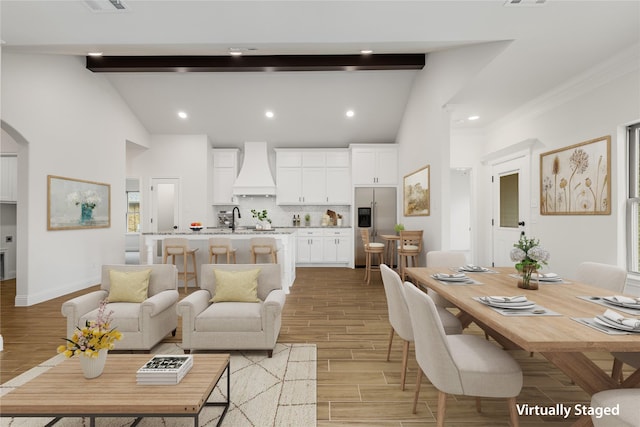 living area with wood finish floors, beam ceiling, arched walkways, and baseboards