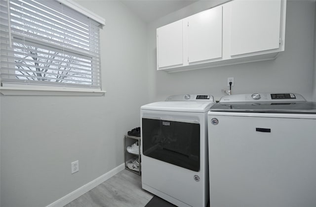 laundry area with cabinets, separate washer and dryer, and light hardwood / wood-style flooring