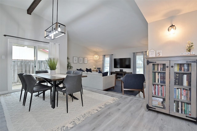 dining room featuring beam ceiling, high vaulted ceiling, and light wood-type flooring