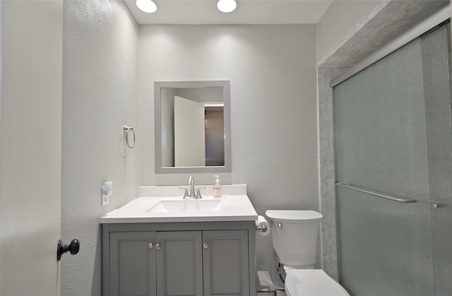 bathroom featuring vanity, toilet, and walk in shower