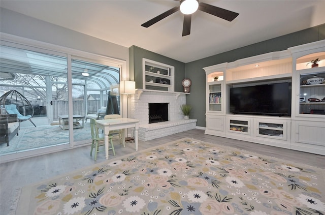 living room featuring ceiling fan, wood-type flooring, and a fireplace