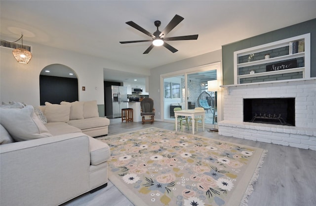 living room with a fireplace, light hardwood / wood-style floors, and ceiling fan