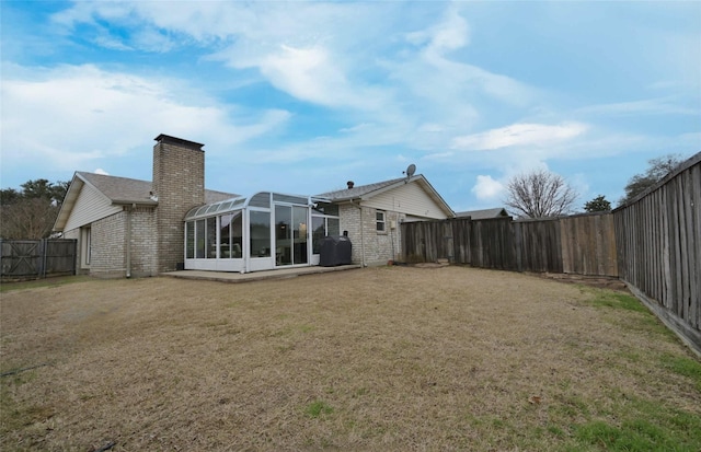 back of house featuring a sunroom and a lawn