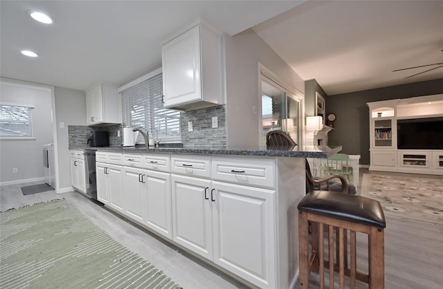kitchen with dark stone counters, white cabinets, a kitchen breakfast bar, and decorative backsplash