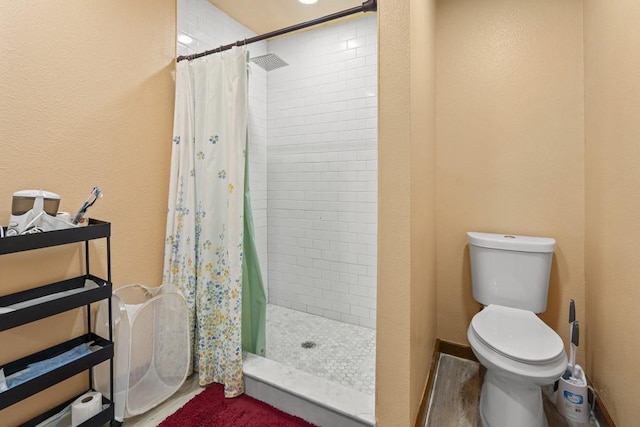 full bath featuring a stall shower, toilet, and baseboards