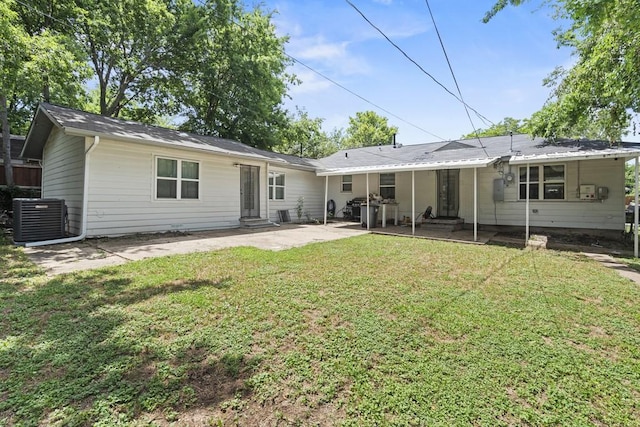 back of property with entry steps, a yard, central AC unit, and a patio area