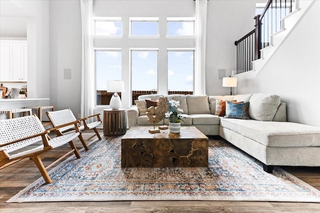 living room with a healthy amount of sunlight, hardwood / wood-style floors, and a towering ceiling