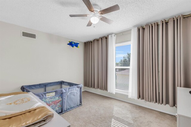 living room with ceiling fan, light carpet, and a textured ceiling
