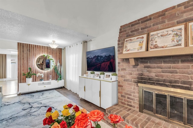 living room with a brick fireplace, hardwood / wood-style floors, and a textured ceiling