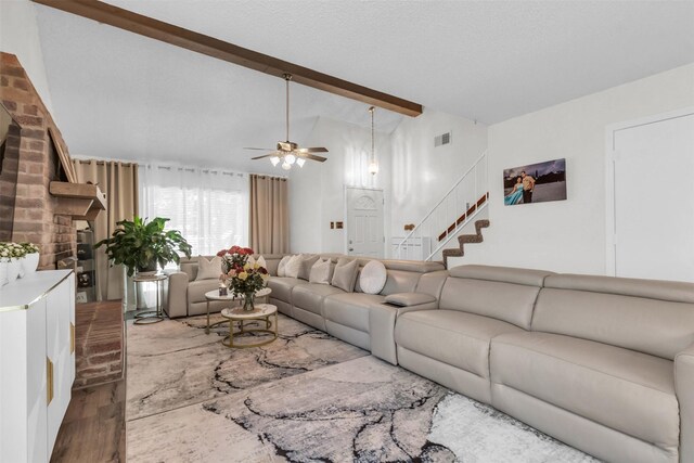 living room with ceiling fan, wood-type flooring, a textured ceiling, and vaulted ceiling with beams