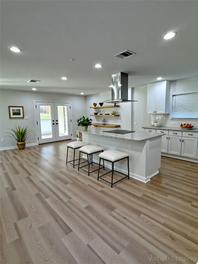 12009 Saddlehorn Ln, Mansfield, TX 76063 - kitchen with exhaust hood, recessed lighting, light wood finished floors, white cabinetry, and french doors