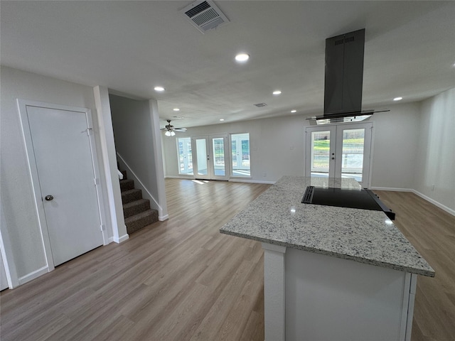 12009 Saddlehorn Ln, Mansfield, TX 76063 - kitchen featuring french doors, light wood-style floors, black electric cooktop, recessed lighting, and island range hood