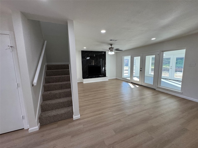 12009 Saddlehorn Ln, Mansfield, TX 76063 - unfurnished living room with light wood-style floors, a high end fireplace, recessed lighting, stairway, and a ceiling fan