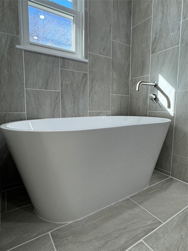 12009 Saddlehorn Ln, Mansfield, TX 76063 - bathroom featuring tile walls, a soaking tub, and marble look tile flooring