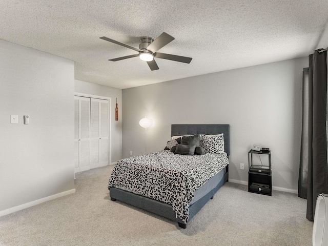 bedroom featuring a textured ceiling, a closet, ceiling fan, and light colored carpet