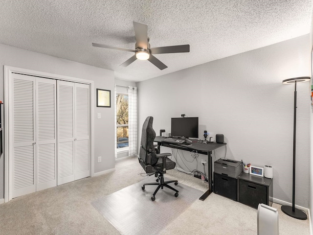 office area with a textured ceiling, light colored carpet, and ceiling fan